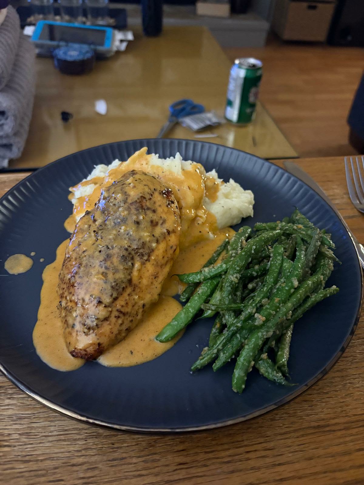 Eat My Dust blackened chicken breast in a creamy paprika sauce with mashed potatoes and green beans on a dark blue plate